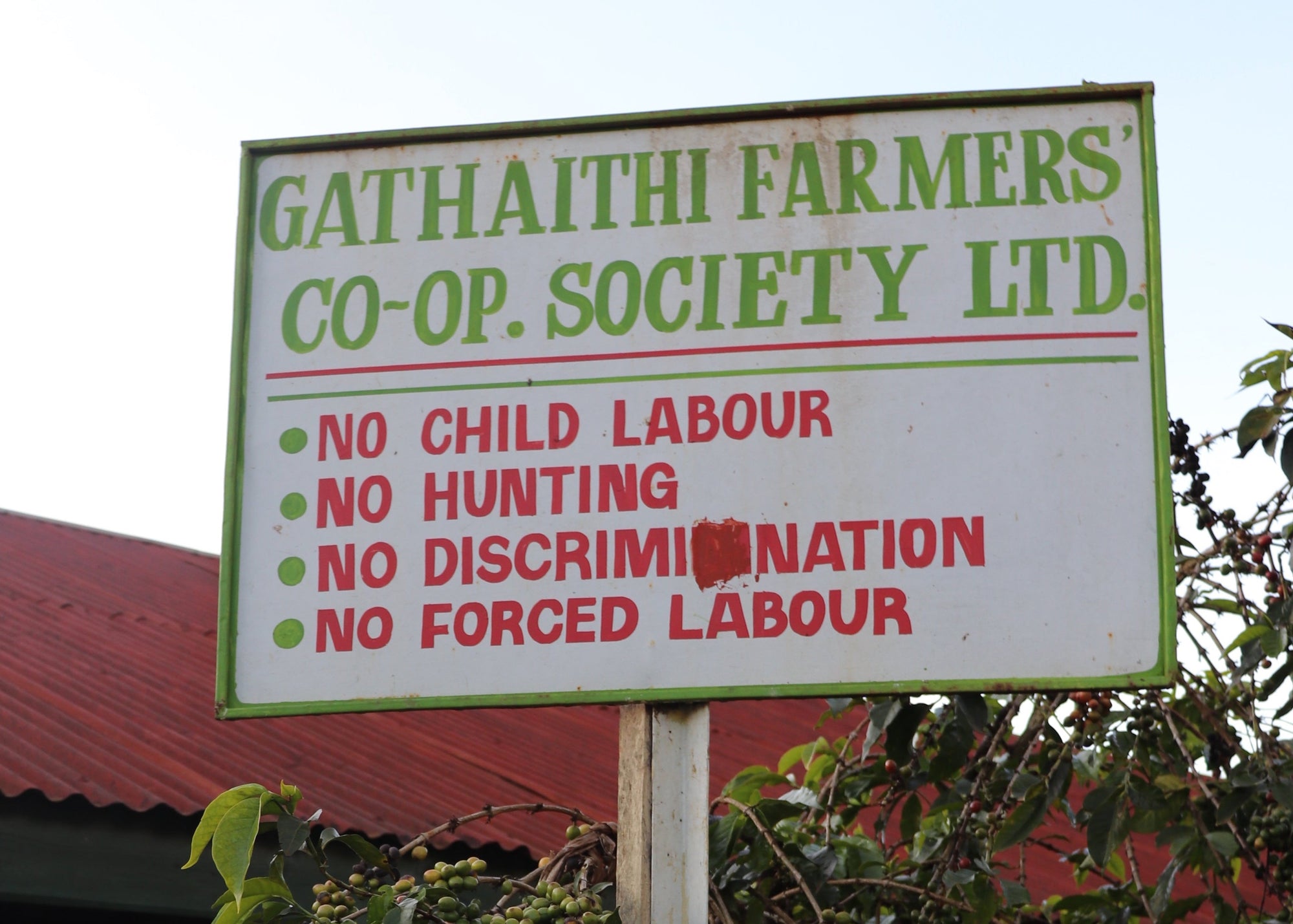 Signboard of Gathaithi Farmers Co-op Society Ltd. with ethical policies in front of a building.
